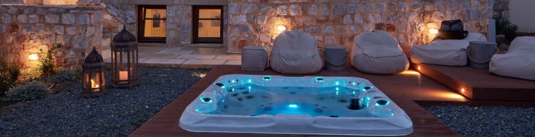 Ein Outdoor-Markenwhirlpool vor einem Haus in abendlicher Atmosphäre.