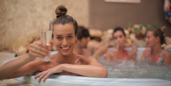Frau mit Glas und Freunde relaxen im Whirlpool XXL