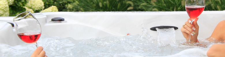 Grossaufnahme von Aperol Spritz Gläsern, mit denen Frauen im Whirlpool anstossen.