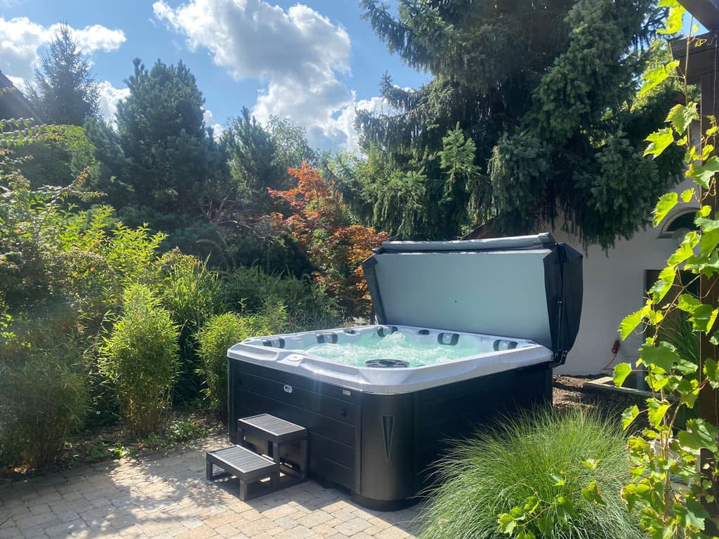 Whirlpool aus unserem Shop in einem idyllischen Garten mit hochgeklapptem Cover
